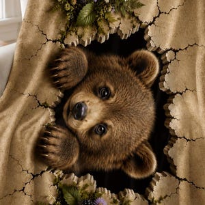 May include: A tan throw blanket featuring a 3D-effect design of a brown bear cub peeking through a cracked wall opening. The edges of the crack are decorated with green ferns, purple wildflowers, white daisies, and dark blackberries.