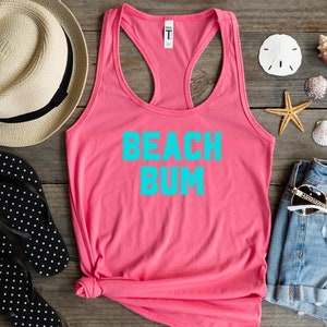 May include: Pink tank top with the text "Beach Bum" in turquoise blue lettering.