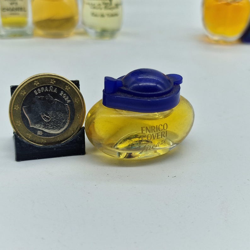 K&ouml;nnte beinhalten: Ein kleiner Parf&uuml;mflakon mit gelber Fl&uuml;ssigkeit und blauem Deckel. Auf der Flasche steht "ENRICO COVERI Firenze". Eine Euro-M&uuml;nze liegt daneben zum Gr&ouml;&szlig;envergleich.