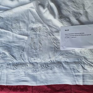 May include: White embroidered linen tablecloth with a monogram in the centre. The tablecloth is 270 x 270 cm / 106 x 106 inches and is made of 100% flax.