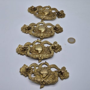 Könnte beinhalten: Vier verzierte goldfarbene Schubladenknöpfe mit herzförmigem Design. Jeder Knopf hat ein detailliertes Blumenmuster und einen kleinen Knopf.