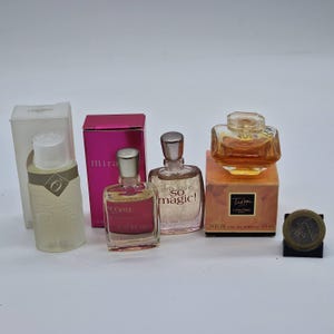 Pode incluir: Uma coleção de frascos de perfume em miniatura, incluindo produtos Lancôme. Os frascos variam em forma e cor, alguns em caixas. Um frasco é rotulado "Mira", e outro "So Magic!". Uma moeda está incluída para escala.