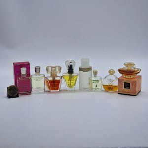 Puede incluir: Colección de frascos de perfume en miniatura de varias formas y tamaños. Los frascos contienen líquidos de diferentes colores, incluyendo rosa, amarillo y transparente. Algunos tienen tapones decorativos.