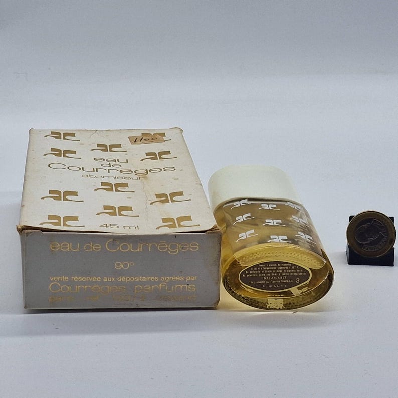 May include: A vintage Eau de Courr&egrave;ges perfume bottle and box. The bottle is cylindrical with a white cap and the box is rectangular. Both feature the Courr&egrave;ges logo. The bottle contains 45 ml of perfume.