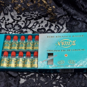 May include: A teal box containing twelve miniature bottles of Eau de Cologne. Each bottle has a gold label and a red cap. The box is labeled "Echt K&ouml;lnisch Wasser" and "Original Eau de Cologne".