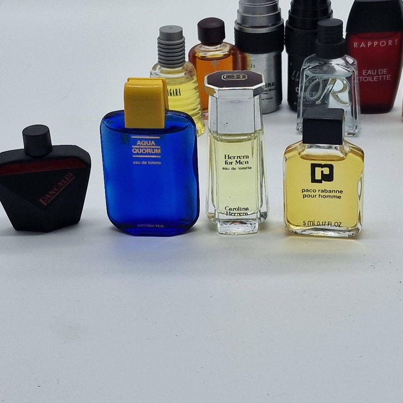 May include: A collection of miniature perfume bottles in various shapes and colors. The bottles include brands like Aqua Quorum, Herrera for Men, and Paco Rabanne. The bottles are arranged on a white surface.