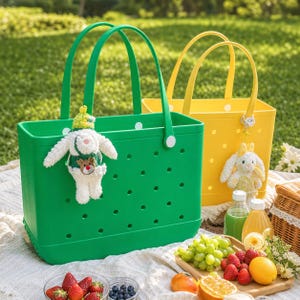 May include: A bright green rectangular tote bag with circular cutouts and a white plush rabbit keychain, positioned next to a yellow tote bag with a similar design and a yellow plush rabbit keychain, both featuring dual handles.