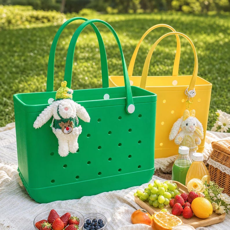 May include: A bright green rectangular tote bag with circular cutouts and a white plush rabbit keychain, positioned next to a yellow tote bag with a similar design and a yellow plush rabbit keychain, both featuring dual handles.