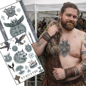 Puede incluir: Dos hojas de tatuajes temporales con diseños vikingos, que incluyen hachas, escudos, cuervos, lobos y un barco vikingo. Los tatuajes son en blanco y negro. Un hombre con tatuajes vikingos y una estola de piel está en el fondo.