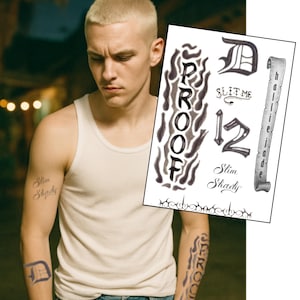 May include: A man wearing a white tank top and blue jeans. The man has a buzz cut and tattoos on his arms that say "Slim Shady", "Proof", and "D". A sheet of temporary tattoos is visible.