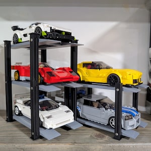 May include: A multi-level black and gray car storage unit holds six toy cars. The cars are various colors, including white, red, yellow, and gray. The unit is made of plastic and has a ramp for each level.