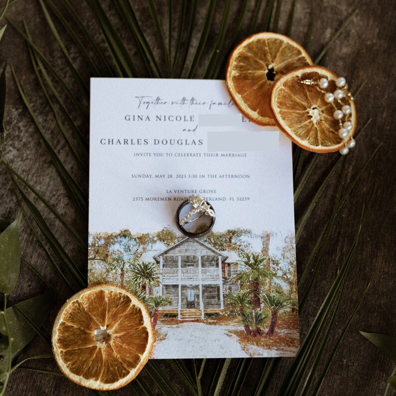 K&ouml;nnte beinhalten: Hochzeitseinladung mit den Namen GINA NICOLE und CHARLES DOUGLAS, mit einer Aquarellillustration eines Hauses. Die Einladung ist mit getrockneten Orangenscheiben, einer Perlenkette und Eheringen verziert. Gr&uuml;ne Palmbl&auml;tter sind um die Einladung angeordnet.
