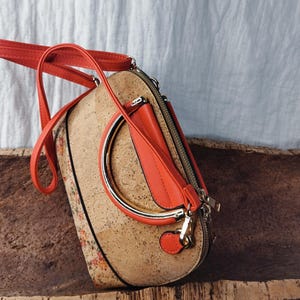 Elegante bolso de corcho con correa roja ajustable, portátil y con estilo.