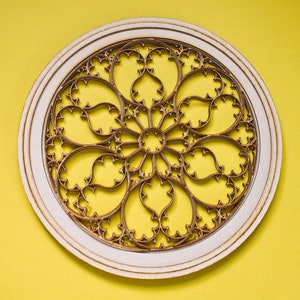 May include: A white circular frame with a detailed, intricate, gold-coloured design resembling a stained glass window.