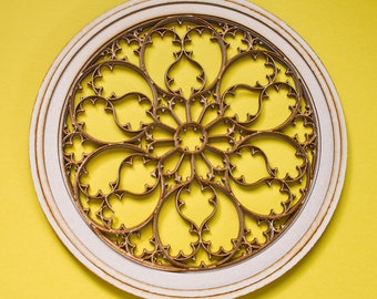 May include: A white circular frame with a detailed, intricate, gold-colored design resembling a stained glass window.