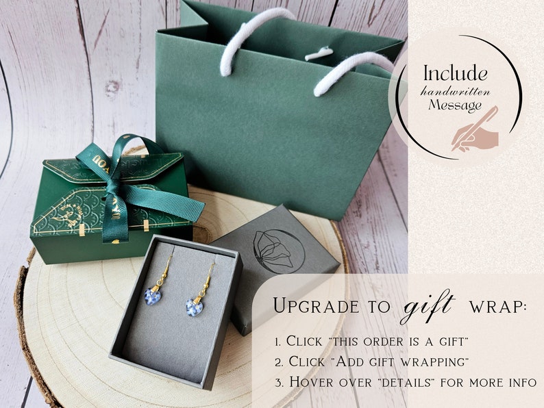 May include: A green gift bag with white handles, a green gift box with a green ribbon, a small gray box with a pair of blue heart-shaped earrings, and a sign that says "Upgrade to gift wrap: 1. Click "This order is a gift" 2. Click "Add gift wrapping" 3. Hover over "Details" for more info".