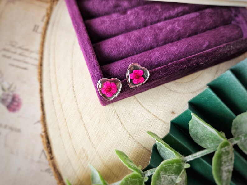 May include: A pair of heart-shaped earrings with a pink flower pressed inside each clear resin heart.