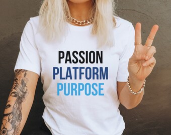 May include: A white t-shirt with the words "Passion Platform Purpose" printed in black and blue text.