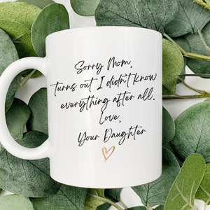 May include: White ceramic mug with a black handwritten message that reads "Sorry Mom, Turns out I didn't know everything after all. Love, Your Daughter" with a gold heart.