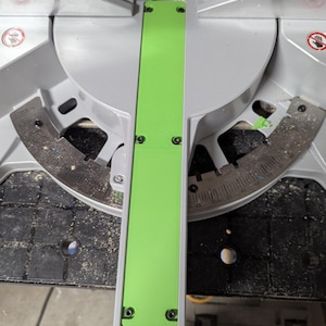 May include: A miter saw with a bright green guide and a silver blade. The saw has a black base and is designed for cutting wood at various angles. The blade guard is visible, and the saw appears to be in good condition.