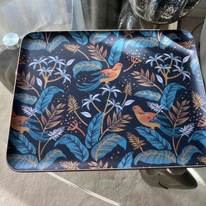 May include: A rectangular serving tray with a black background and a tropical print featuring blue and gold leaves, orange birds, and white flowers.