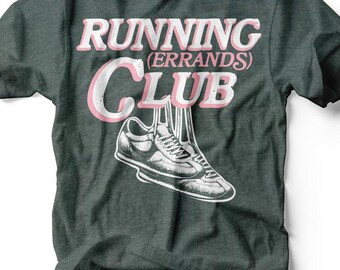 Könnte beinhalten: Dunkelgraues T-Shirt mit dem Schriftzug "RUNNING (ERRANDS) CLUB" in Rosa und Weiß. Eine schwarz-weiße Illustration eines Laufschuhs befindet sich darunter. Der Markenname "RUBY'S RUBBISH" steht unten.