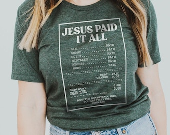 Könnte beinhalten: Dunkelgrünes T-Shirt mit dem Text "JESUS PAID IT ALL" in einem quittungsähnlichen Design. Das Shirt listet verschiedene Sünden auf und erklärt sie als "BEZAHLT". Auf dem Shirt steht der Bibelvers Johannes 8:36.