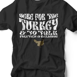 May include: Black t-shirt with white text that reads "HERE FOR THE TURKEY & TO TALK POLITICS & RELIGION." A small illustration of a turkey is below the text. The shirt is made of a soft material.