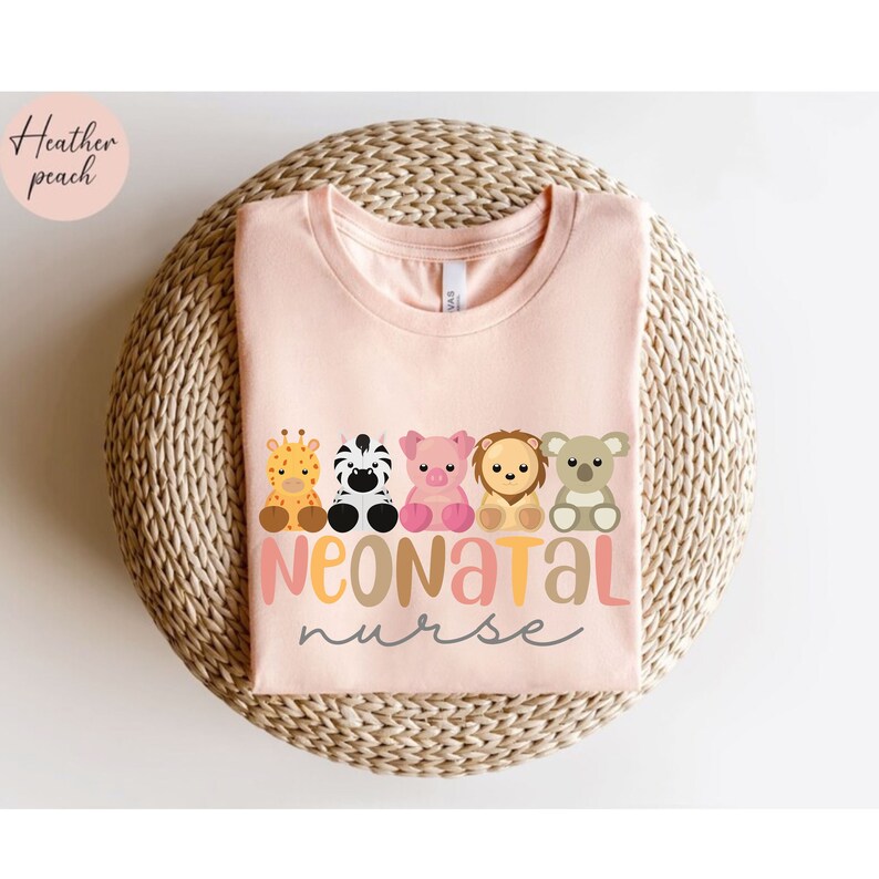 Puede incluir: Una camiseta rosa con una l&iacute;nea de ilustraciones de animales lindos y el texto "Neonatal Nurse".