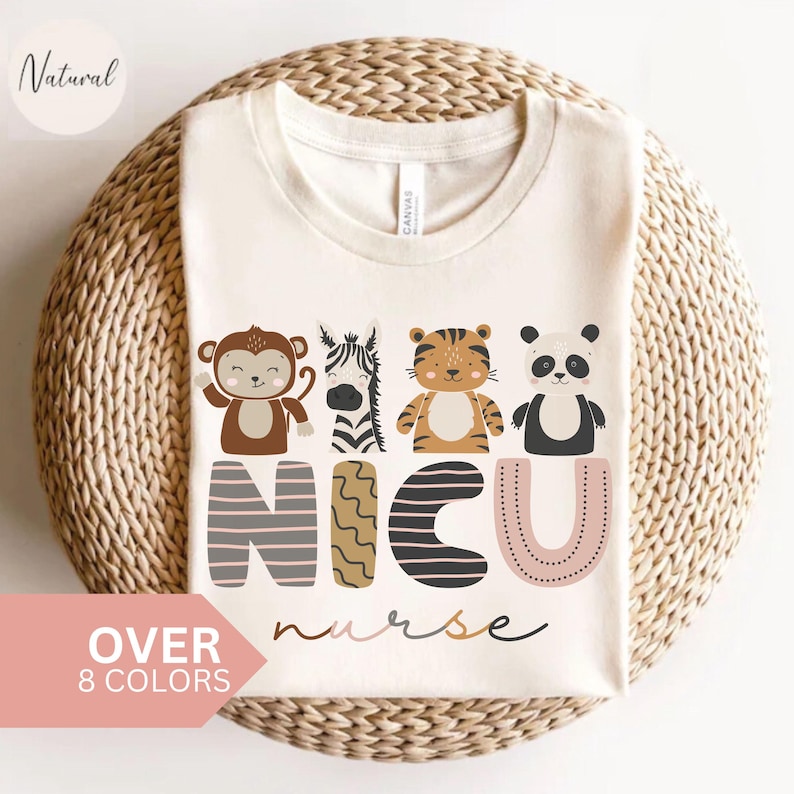 Pode incluir: Camiseta creme com um design de macaco, zebra, tigre e panda acima das palavras "NICU nurse". A camisa tamb&eacute;m tem o texto "OVER 8 COLORS" em uma faixa rosa e a palavra "Natural" em um c&iacute;rculo.