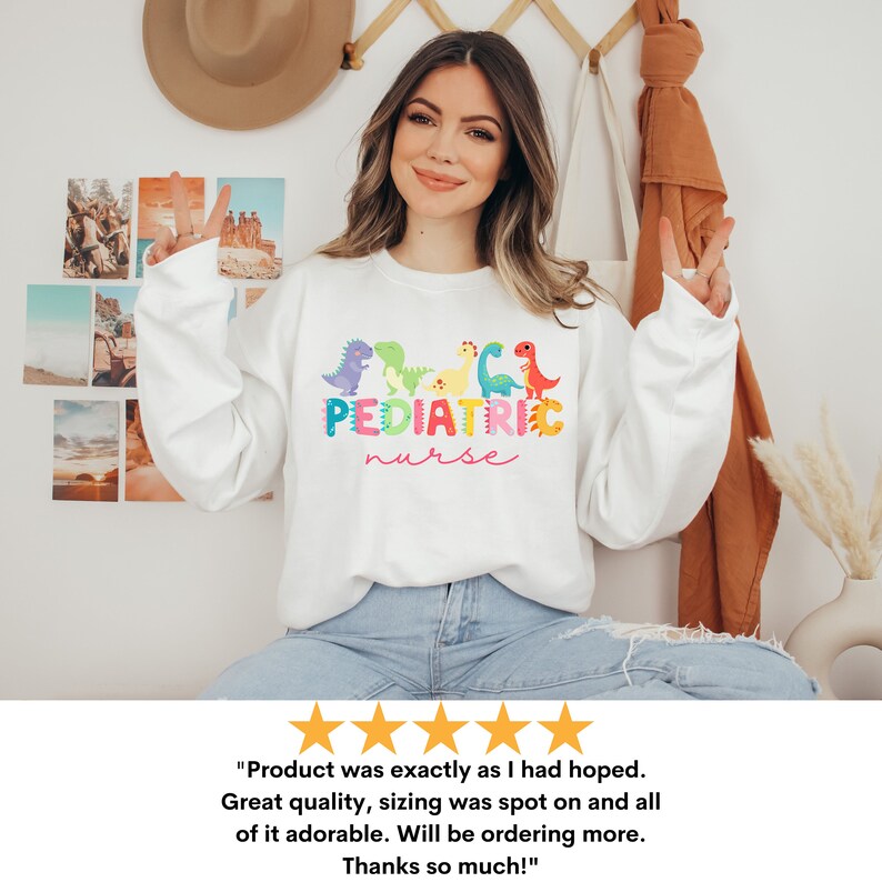May include: White sweatshirt with a colorful graphic of dinosaurs and the text "PEDIATRIC nurse".