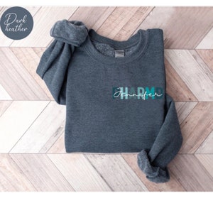 May include: Dark heather grey sweatshirt with the text "Jennifer" and "D.H.A.R.M.D." in a colorful gradient design.