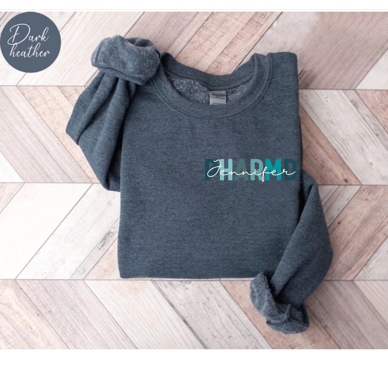 May include: Dark heather grey sweatshirt with the text "Jennifer" and "D.H.A.R.M.D." in a colorful gradient design.