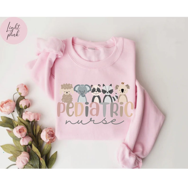 Puede incluir: Una sudadera rosa claro con un gr&aacute;fico de cinco animales y el texto "Pediatric Nurse".