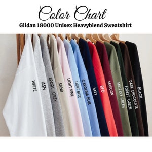 May include: Color chart showing 12 different colors of Gildan 18000 Unisex Heavyblend Sweatshirts. The colors are: Black, Dark Chocolate, Forest Green, Military Green, Maroon, Red, Navy, Carolina Blue, Light Blue, Light Pink, Sand, Sport Grey, and Ash.