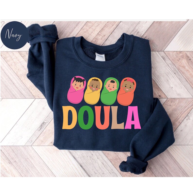 May include: Navy blue sweatshirt with a graphic of four babies in colorful swaddles and the word "DOULA" in rainbow letters.