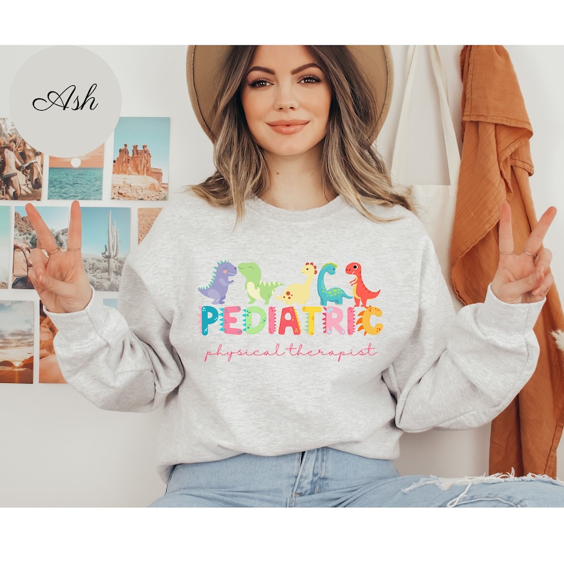 May include: A gray sweatshirt with a graphic design of colorful dinosaurs and the text 'PEDIATRIC physical therapist'.