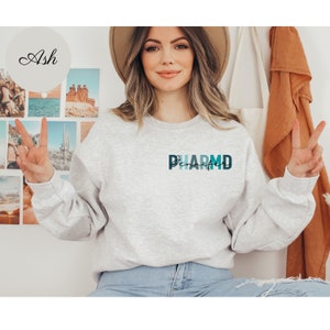 May include: A gray sweatshirt with a blue and green graphic that says "PHARM'D" on the front.