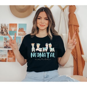 Pu&ograve; includere: Una maglietta nera con una grafica di quattro lama che indossano cappelli e un design blu turchese che dice "NEONATAL nurse".