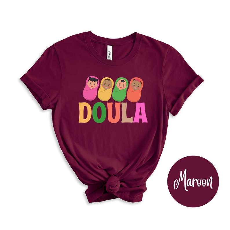 May include: Maroon t-shirt with a graphic of four babies in swaddles and the word "DOULA" in colorful letters.