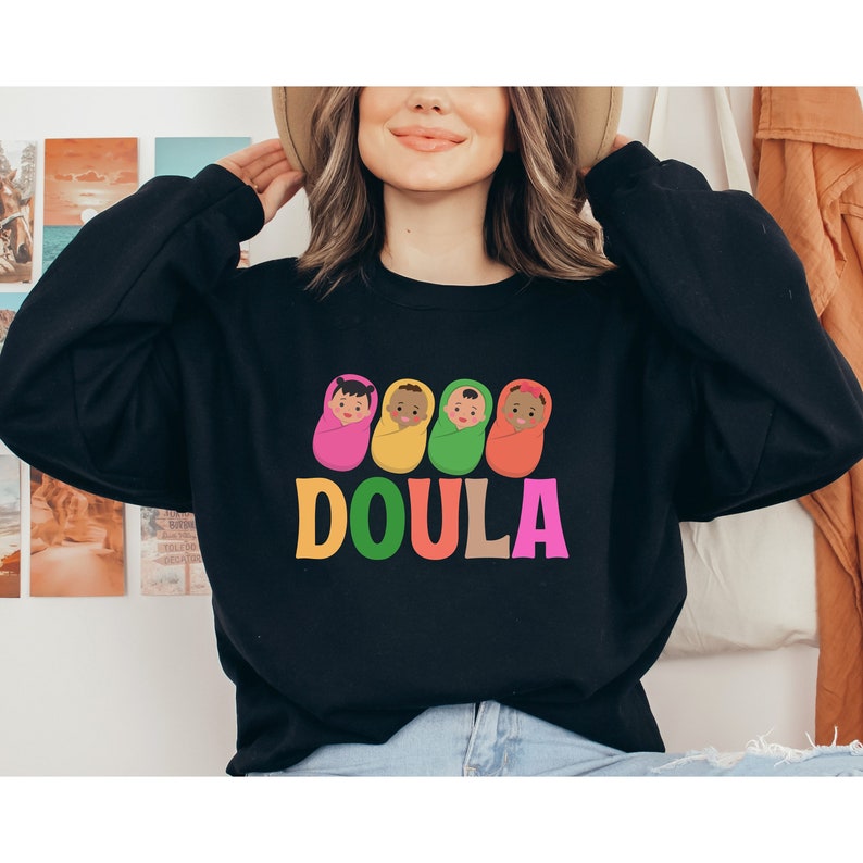 May include: Black sweatshirt with a graphic of four babies in colorful swaddles and the word "DOULA" in rainbow letters.