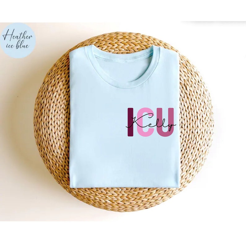 May include: A light blue t-shirt with the text "ICU Kelly" in pink and burgundy letters. The letters are stacked on top of each other, with the "I" and "U" being larger than the "C". The text "Kelly" is written in cursive below the letters.