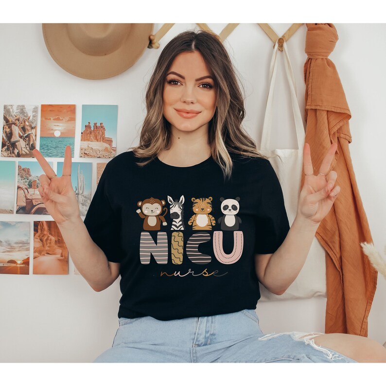 Pode incluir: Camiseta preta com um gr&aacute;fico colorido com um macaco, zebra, tigre e panda acima do texto "NICU nurse" em uma fonte l&uacute;dica. A camisa &eacute; feita de um material macio.