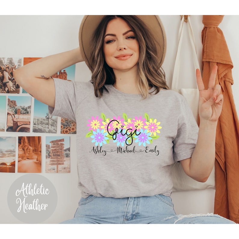 May include: Gray t-shirt with a floral design and the word "Gigi" in pink and black lettering. Below the floral design, the names "Ashley", "Michael", and "Emily" are written in black cursive.