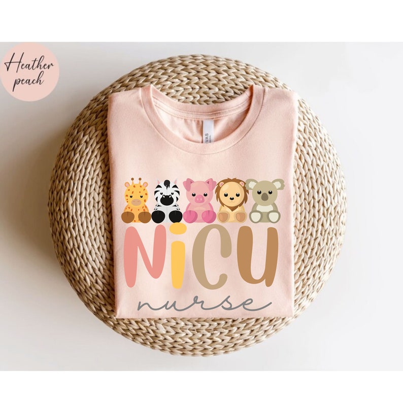 May include: A pink t-shirt with the words "NICU nurse" in colorful letters. A row of five cartoon animals are above the text, including a giraffe, zebra, pig, lion, and koala.