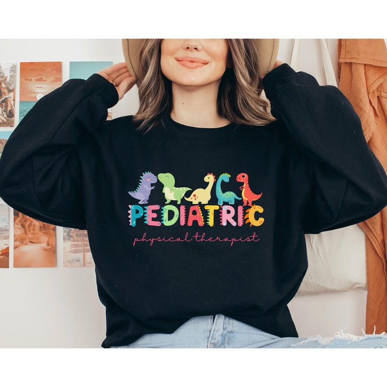 May include: A black sweatshirt with a colorful graphic of dinosaurs and the text 'Pediatric physical therapist'.