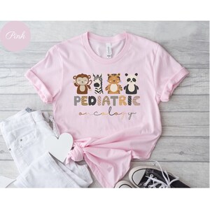 May include: Pink t-shirt with a graphic of animals and the text "PEDIATRIC ONCOLOGY".