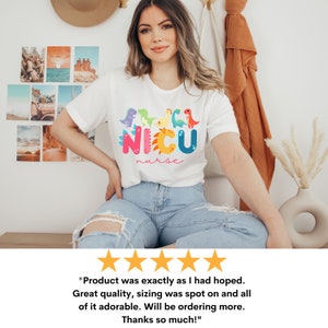 Pu&ograve; includere: T-shirt bianco con una grafica di dinosauri colorati e la scritta "NICU nurse". Il design presenta vari dinosauri dei cartoni animati sopra il testo. La maglietta &egrave; uno stile casual.