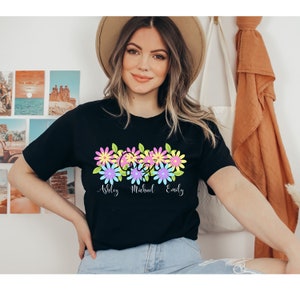 May include: Black t-shirt with a floral design and the names "Ashley", "Michael", and "Emily" printed below.