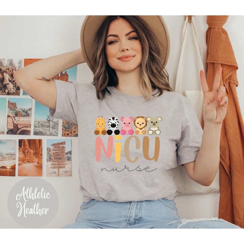 May include: A gray t-shirt with a graphic of five cartoon animals sitting in a row. The animals are a giraffe, zebra, pig, lion, and koala. The text "NICU nurse" is written below the animals in pink and yellow letters.